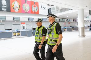 Two Police Officers walking through an airport.