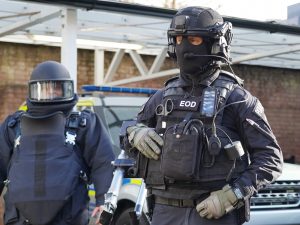 Two Explosives Officers standing in front of a police car